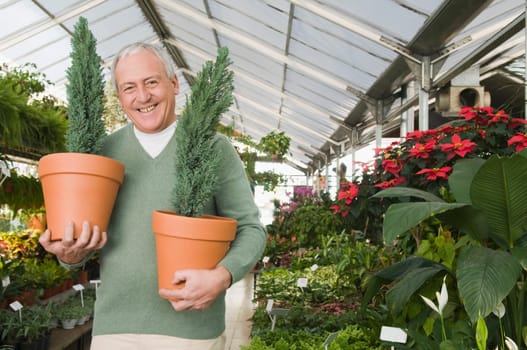 Man holding potted plants in a garden center