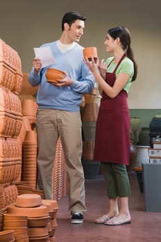 Female sales clerk showing pottery to a man