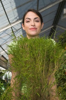 Portrait of a woman carrying a potted plant and smiling