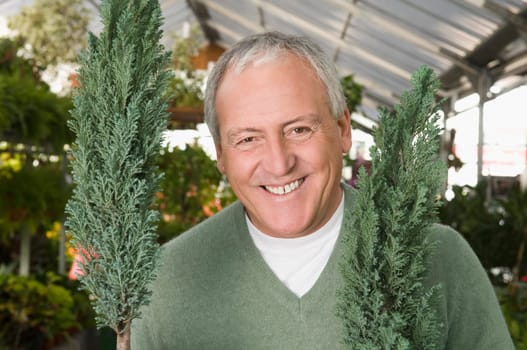 Man smiling with potted plants in a garden center