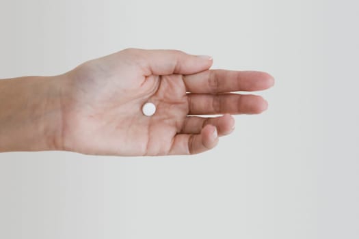 Close-up of a person's hand holding a pill