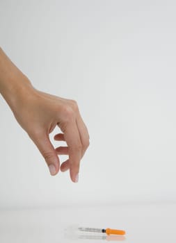 Close-up of a person's hand picking up a syringe