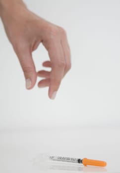 Close-up of a person's hand picking up a syringe