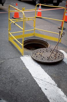 Manhole surrounded by a barricade on the road