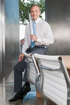 Businessman holding a chart and smiling in a board room