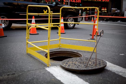 Manhole surrounded by a barricade on the road