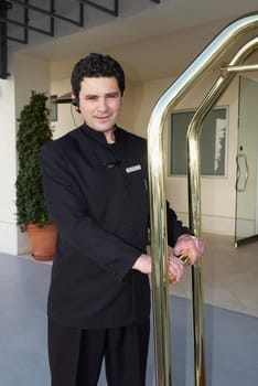 Doorman holding a luggage cart