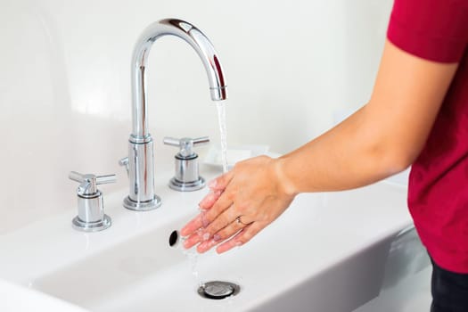 Washing hands under running water in washbasin from close up. palm zoom in. Woman rubbing soap. Concept of hygiene and skin care.