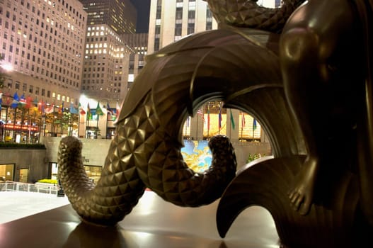 Close-up of a statue with buildings lit up at night in the background
