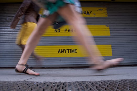 Low section view of two women walking in front of a No Parking Sign