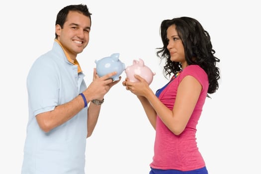 Side profile of a young couple holding piggy banks and smiling