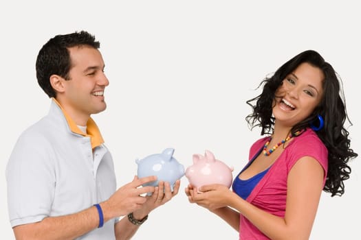 Side profile of a young couple holding piggy banks and smiling
