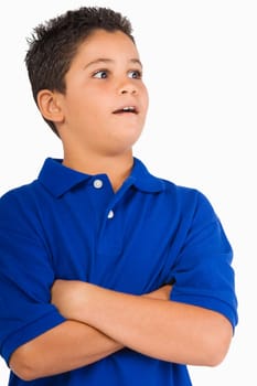 Close-up of a boy standing with his arms crossed and looking surprised