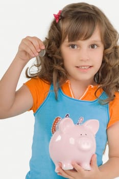 Portrait of a girl putting a coin into a piggy bank