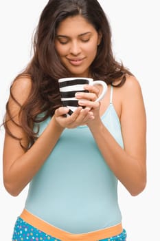 Close-up of a young woman holding a mug of coffee and smiling