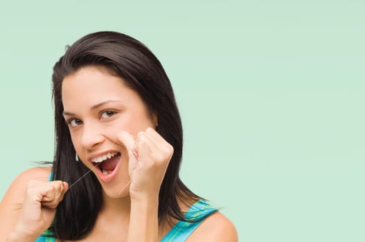 Portrait of a young woman flossing her teeth