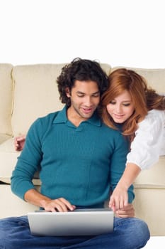 Young man using a laptop with a young woman leaning over him