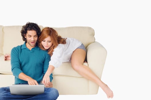 Young man using a laptop with a young woman leaning over him