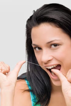 Portrait of a young woman flossing her teeth