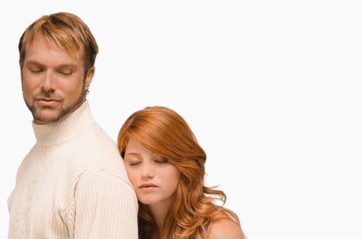 Close-up of a young woman resting her face on the shoulder of a mid adult man