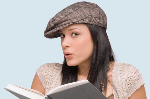 Portrait of a young woman whistling with a book in front of her
