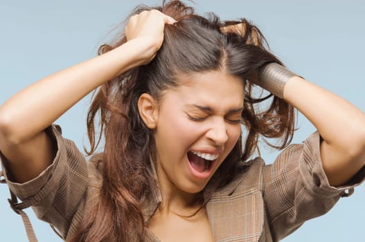 Close-up of a young woman screaming with her hands in her hair