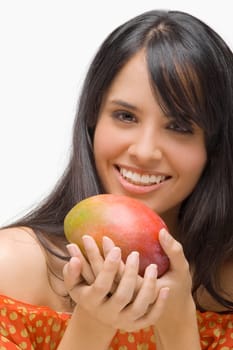 Portrait of a young woman holding a mango and smiling