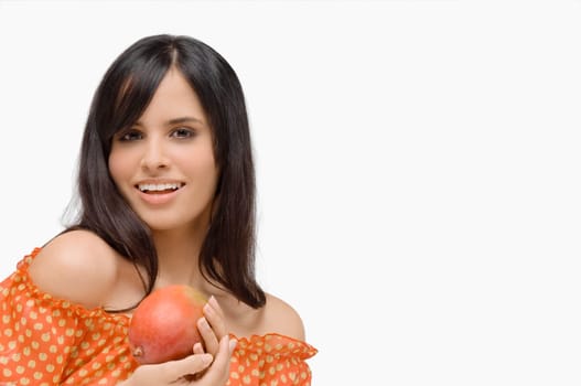 Portrait of a young woman holding a mango and smiling