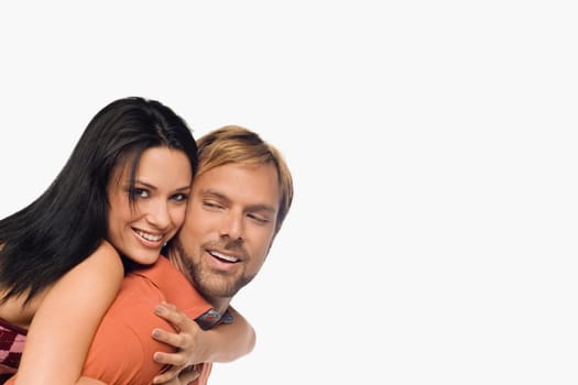 Portrait of a young woman riding piggyback on a mid adult man