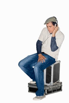 Young man sitting on trunks and listening to music