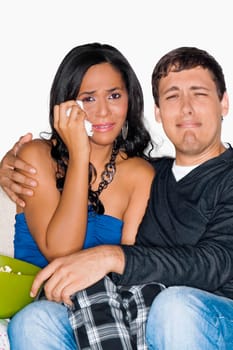 Young man and a teenage girl watching television and crying