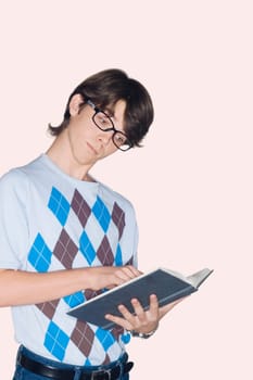 Teenage boy standing and reading a book