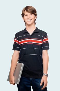 Portrait of a teenage boy holding a laptop and smiling
