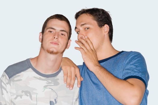 Portrait of a young man whispering into a young man's ear