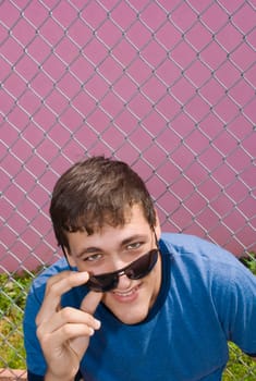 Portrait of a young man holding sunglasses and smiling