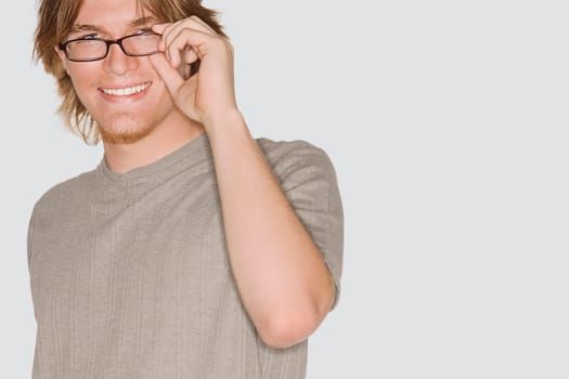 Portrait of a young man adjusting his eyeglasses and smiling