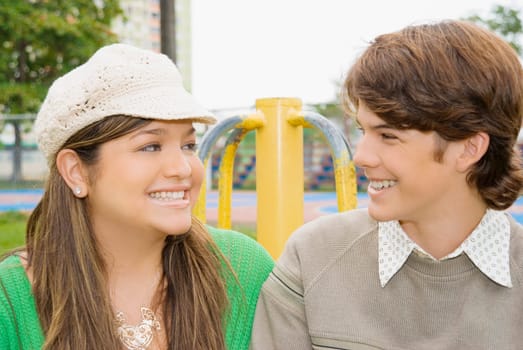 Close-up of a young woman and a teenage boy looking at each other and smiling