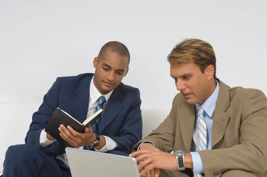 Two businessmen looking at a laptop and having a discussion