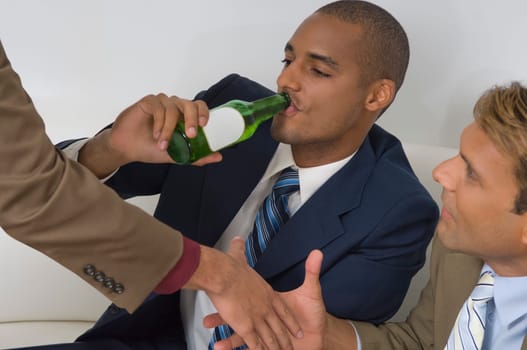 Businessman drinking beer with two businessmen shaking hands beside him