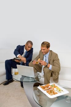 Two businessmen sitting on a couch and having a discussion