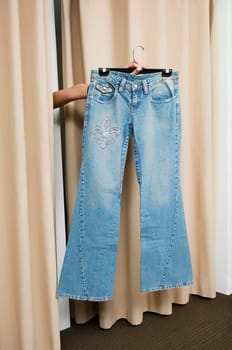 Person's hand showing a jeans through curtains