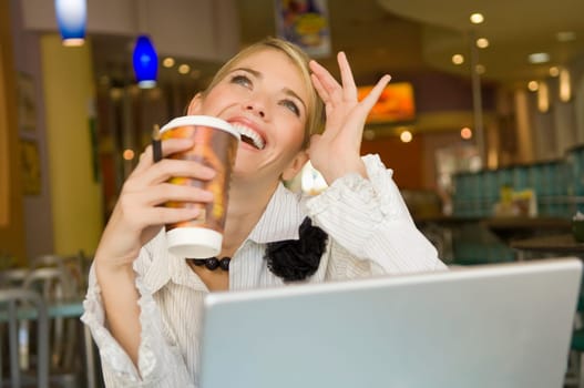 Businesswoman holding a disposable cup and smiling in a restaurant