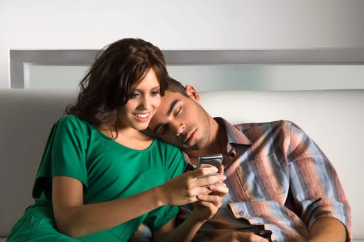 Young woman using a mobile phone and a young man leaning on her shoulder