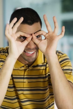 Close-up of a young man pretending to wear glasses