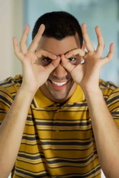 Portrait of a young man pretending to wear glasses and smiling
