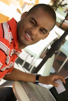 Close-up of a young man winking and holding a credit card