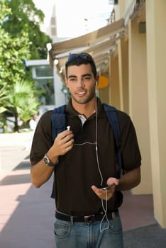 Young man walking and listening to an MP3 player