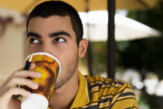 Close-up of a young man drinking coffee from a disposable cup