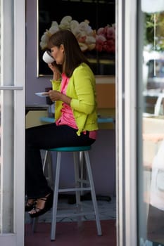 Side profile of a mature woman sitting in a cafe and drinking coffee
