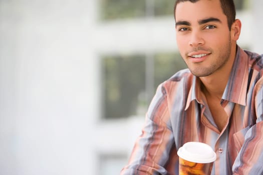 Portrait of a young man holding a cup of cold drink and smiling
